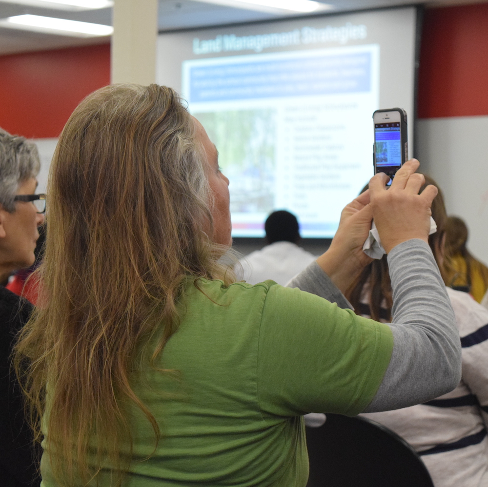 An attendee takes a picture of a presentation slide.